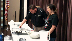 Mr. Chiaro flips pancakes that are cooking as one of the Jefferson teachers looks on.