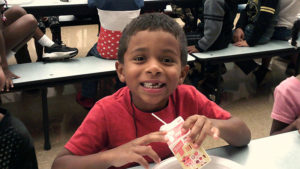 a Jefferson student smiles for the camera as he finishes his pancake breakfast.