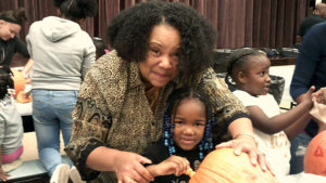 School Board member Regina Patterson helps a kindergarten student clean out her pumpkin.