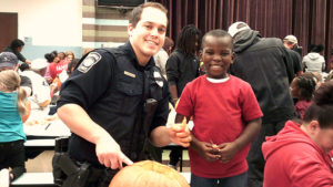Our Jefferson resource officer poses for a picture while helping a kindergarten student with his pumpkin.