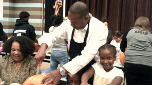 Mayor Franklin helps a kindergarten student carve her pumpkin.
