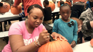 A kindergarten student and her helper working on their pumpkin together.