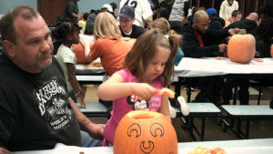 A kindergarten student scooping out her pumpkin.