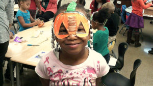 A 1st grade student shows off her completed mask for family day.