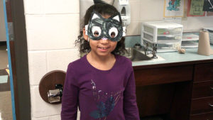 A 1st grade student shows off her completed mask for family day.