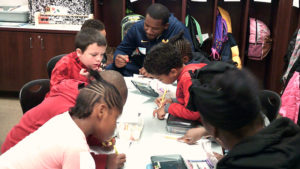 A group of 1st grade students and family members work on their activity for family day.