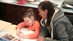 A 1st grade student and her guest work on their family day activity.