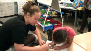 A first grade student and her guest working on their craft.