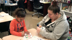 A first grade student and her guest working on their craft.