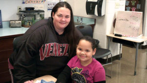 A 1st grade student and her guest smile for the camera during family day.
