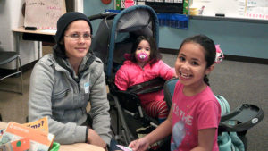 A 1st grade student and her guests take a break from their craft during family day.
