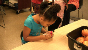 A 1st grade student decorating their pumpkin.