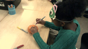 A 1st grade student decorating their pumpkin.