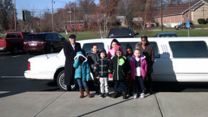 Students and the limo driver pose for a picture in front of the limo.