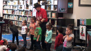 Preschool volunteers help with a magic trick.