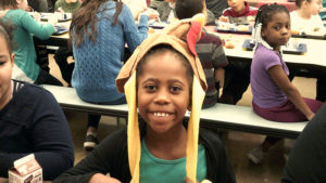 A second grade student shows off her Thanksgiving hat.