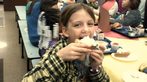 A first grade student enjoying their pumpkin pie.