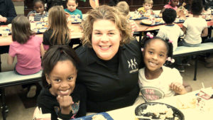 Mrs. Boyer sits with two first grade students for out Thanksgiving lunch.
