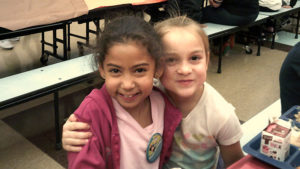 Two first grade students smile for the camera after enjoying their lunch.