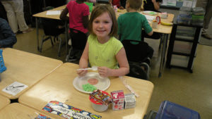A first grader smiles for the camera as she waits to start her breakfast.