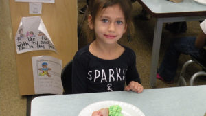 A kindergarten student enjoying her green eggs and ham.