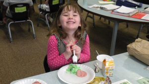 A kindergarten student is excited to try her special breakfast.