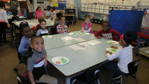 Kindergarten students smile as they start their special breakfast.