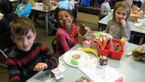 A kindergarten student smiles for the camera as she waits to have breakfast.