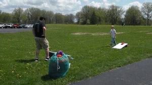 A Harding student and a third grader play cornhole.