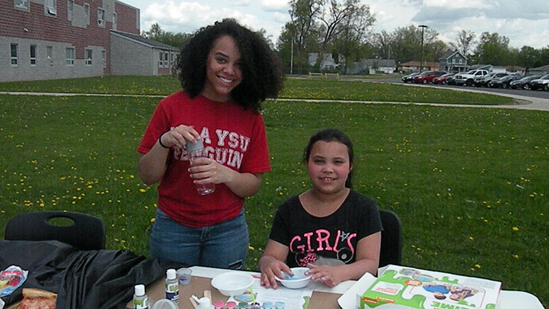 A Harding student works on a craft with a third grader.