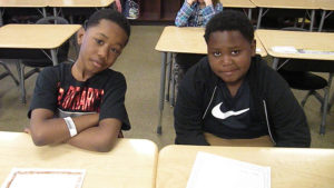 Two second grade students wait for their turn to recite their poetry.