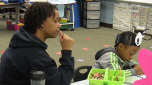 A student works on his poetry as his guest watches.