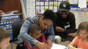 A kindergarten student gets some help working on his poetry activity.
