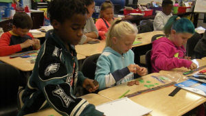 Students at their desks using math tools to figure out a math problem.