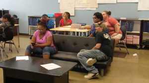 Students and family members listen as their activity is explained to them.