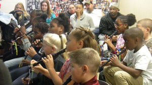 Students perform a piece on their recorders as families watch.