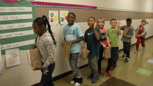Students line up and wait to collect candy from the next classroom.