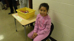 A first grade student passes out candy for the candy walk.