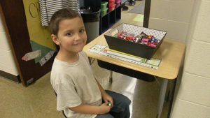 A first grade student passes out candy for the candy walk.