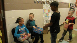 A student waits for his candy from the classroom helpers.