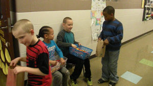 A student gets his candy from one of the classroom helpers.