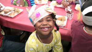 A kindergarten student smiles for the camera after her lunch.