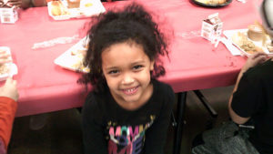 A kindergarten student smiles for the camera after her lunch.