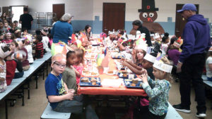 Kindergarten teachers and students enjoy Thanksgiving lunch together.