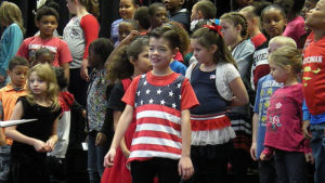 A third grade student stands and waits for the concert to begin.