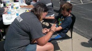 A student gets his arm painted by one of our preschool teachers.