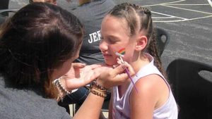 A student get her face painted by one of our kindergarten teachers.