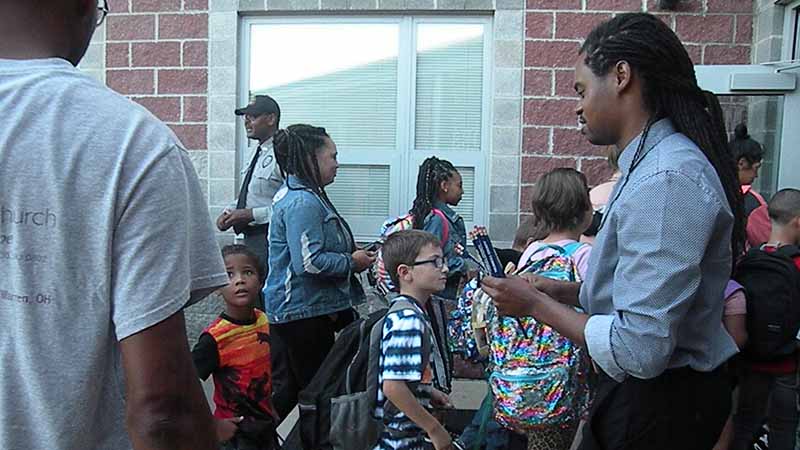 Students are greeted and given pencils as they enter the building.