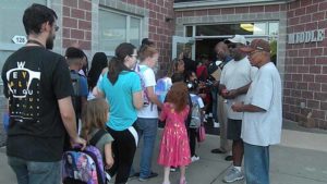 Students receive pencils as they enter the school.