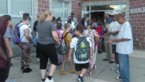 Students and families greeted by men in the community.